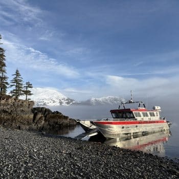 Small group tour landing craft pulled up on a pebble beach in Prince William Sound for a guided walk